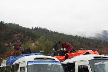 bp-paro-airport-1-loading-baggage Bhutanese guides and bus drivers pack luggage atop two of the ten buses for the drive to Thimphu.